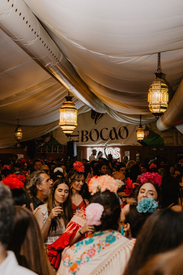 Plano general de la carpa llena, con farolillos y el rótulo «El Bocao»