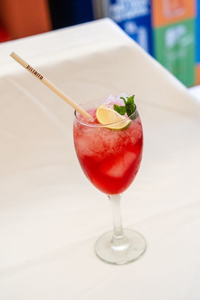 Red cocktail glass with lime and a straw