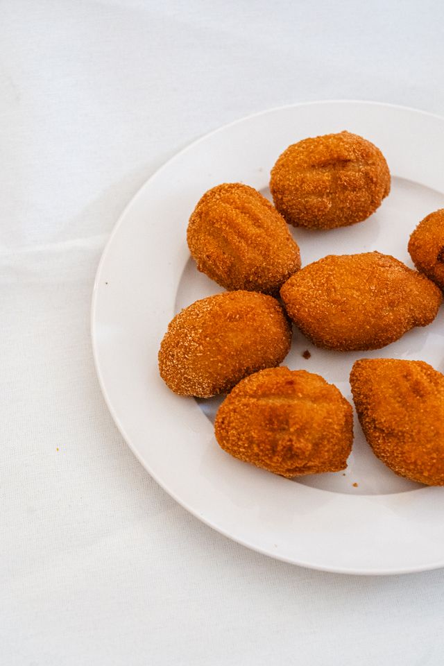 Golden flamenquín croquettes on a white plate