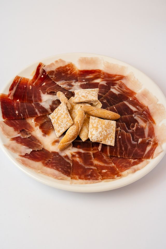 Plate of hand-carved ibérico ham with breadsticks