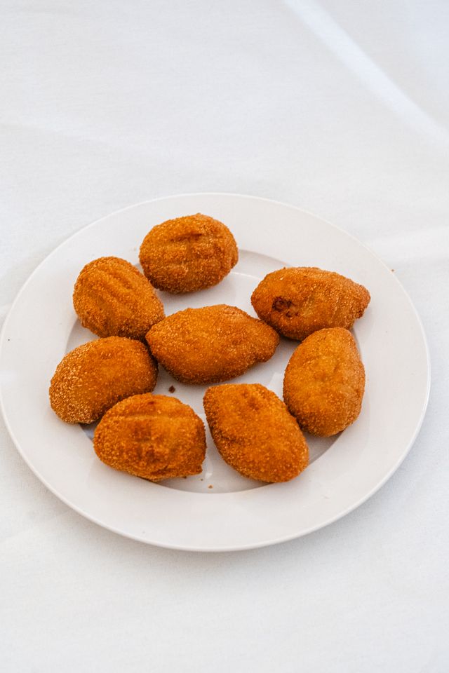 Freshly fried flamenquín bites on a white plate