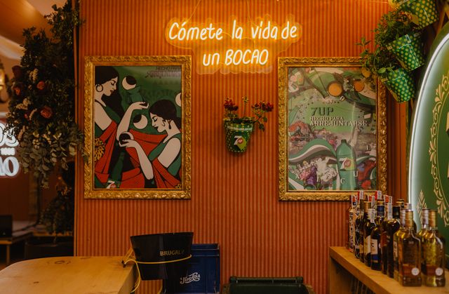 “Cómete la vida de un bocao” neon between two illustrated paintings